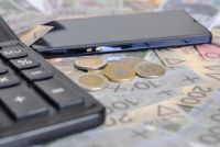 Kalkulator i smartfon leżą na banknotach i monetach